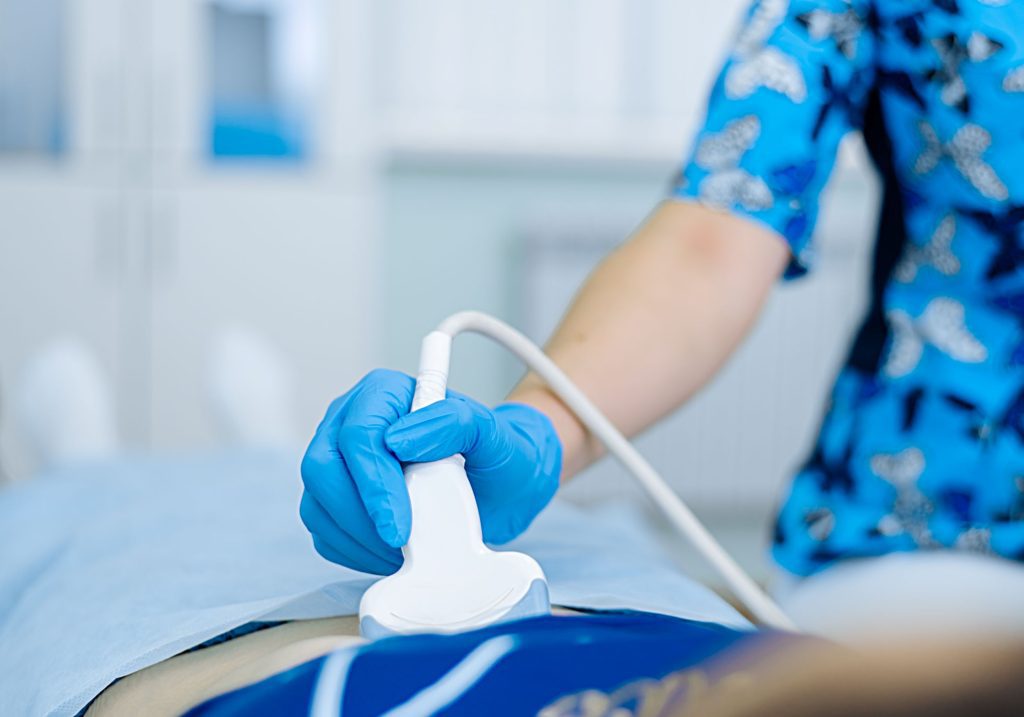 Głowica USG przykłądana przez lekarza w rękawiczkach lekarskich - ilustracja dotycząca USG jąder w Centrum Medycznym neoMedica w w Poznaniu.