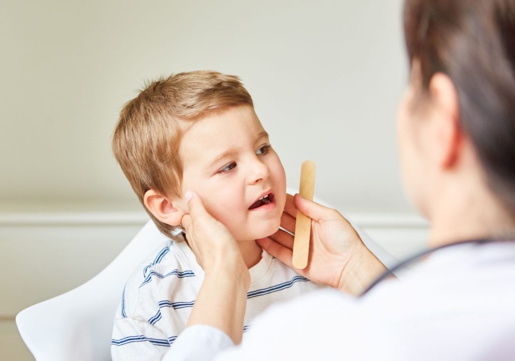 Lekarz dotykający szyi dziecka w celu diagnostyki węzłów chłonnych u dzieci w Centrum Medycznym neoMedica w Poznaniu.