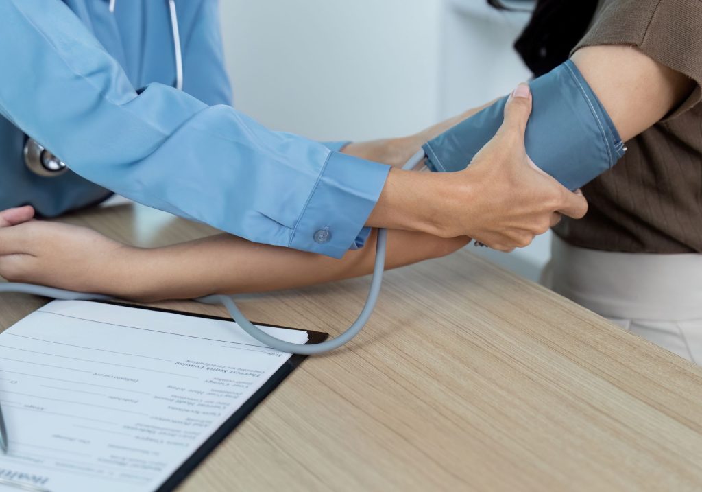Pacjentka na wizycie lekarskiej, podczas której lekarz mierzy ciśnienie ciśnieniomierzem – ilustracja dotycząca oceny zdrowia pracownika w Centrum Medycznym neoMedica w Poznaniu.